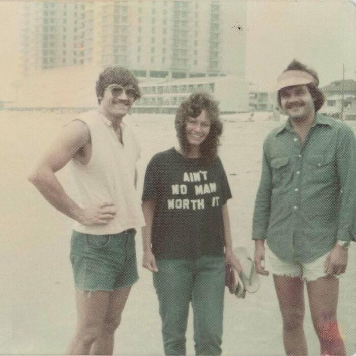 Three people posing on a beach in casual 1970s fashion, captured in an interesting vintage photo reflecting history.