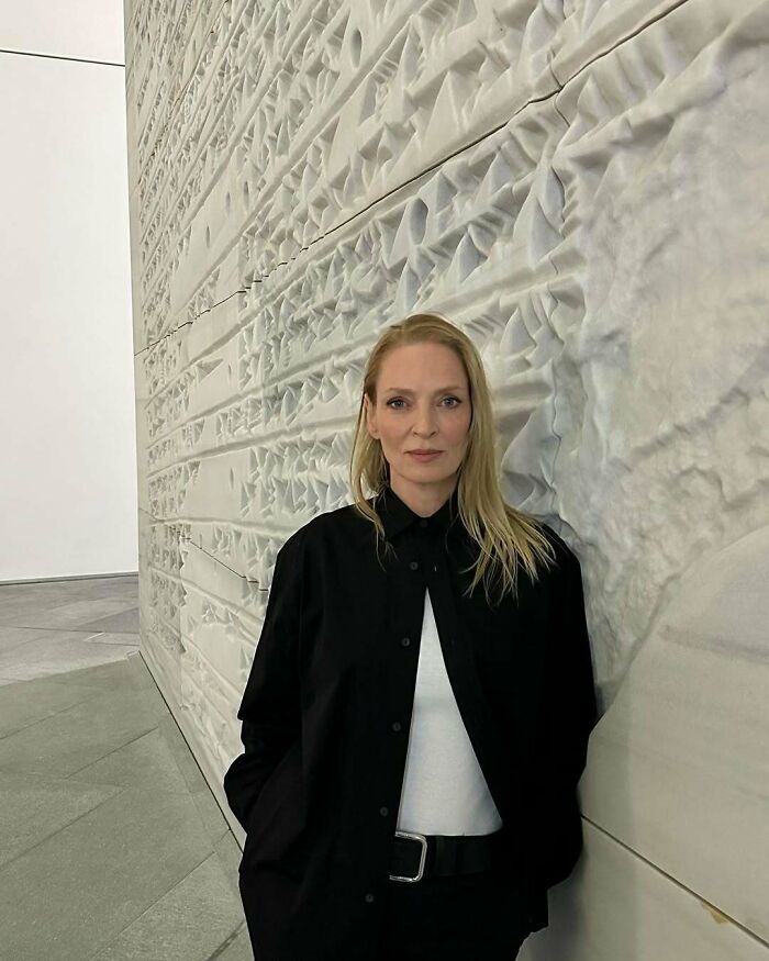 Woman standing by a textured wall, illustrating the topic of celebrities called out for gross hygiene habits.