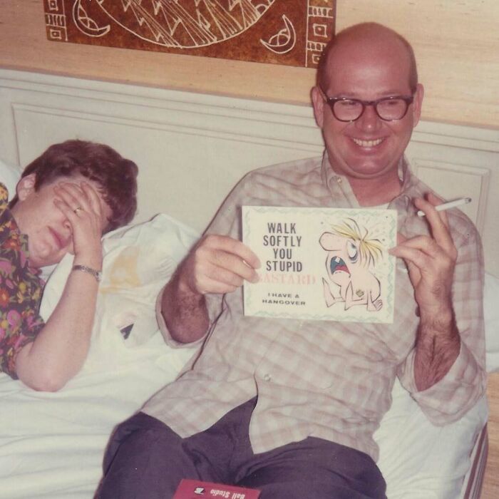 Vintage photo of a man holding a humorous card and a cigarette, capturing an intimate, candid moment in history.