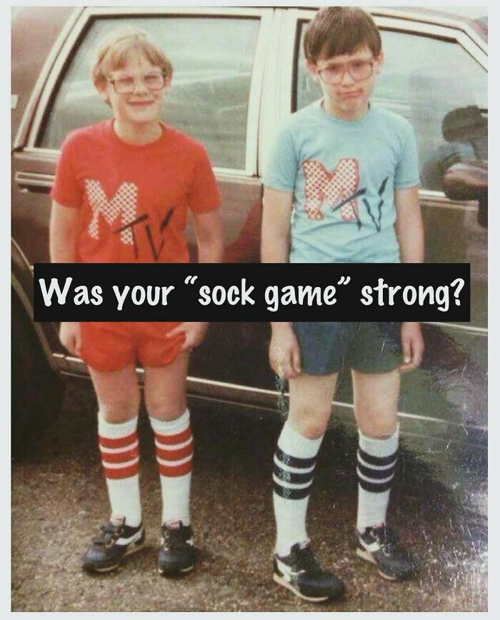 Two boys in colorful retro outfits and striped socks standing by an old car, celebrating the good old 80s style.