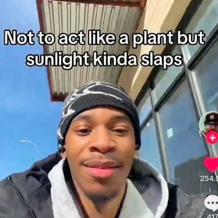 Young man wearing a beanie enjoying sunlight with relatable memes text about sunlight being refreshing outside.