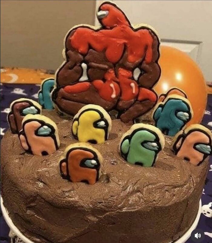Chocolate cake decorated with Among Us character cookies and a muscular red figure, a cringey picture shared on Instagram.