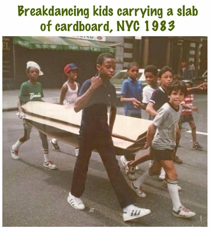 Breakdancing kids carrying cardboard slab in 1983 NYC street scene, celebrating the good old 80s culture and vibe.