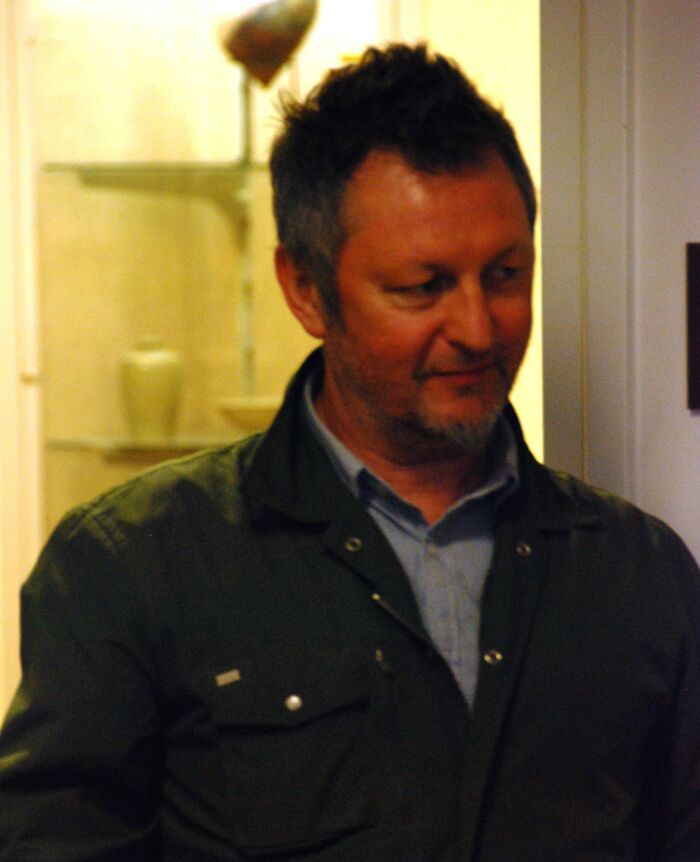 Man in casual dark jacket indoors, representing notable people who passed away in 2025 in a candid moment.