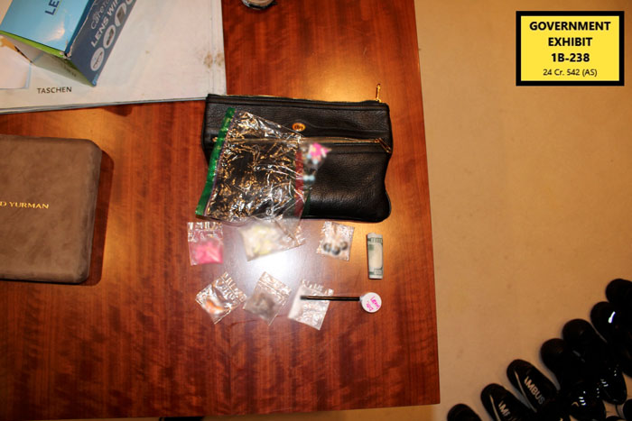 Evidence bags with various items including rolled cash on a wooden table labeled as government exhibit in Diddy trial.