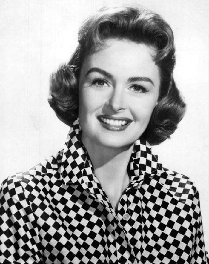 Black and white portrait of a glamorous 1940s Hollywood icon smiling in a checkered blouse.