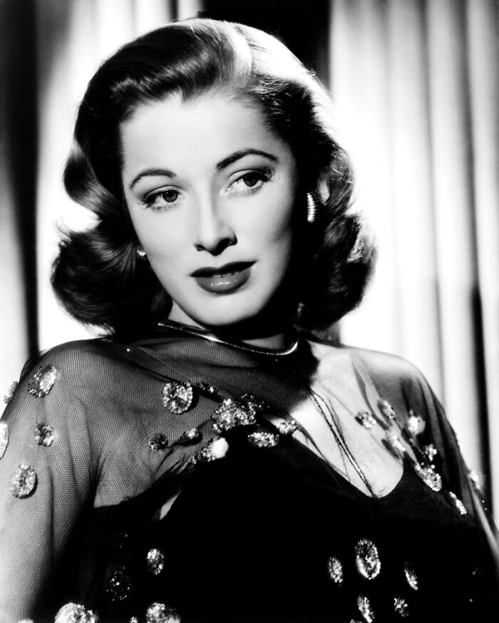 Black and white portrait of a glamorous 1940s icon with styled hair and elegant attire in classic Hollywood fashion.