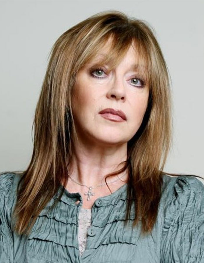 Woman with light brown hair and green eyes wearing a cross necklace, related to Freddie Mercury secret child speaking out.