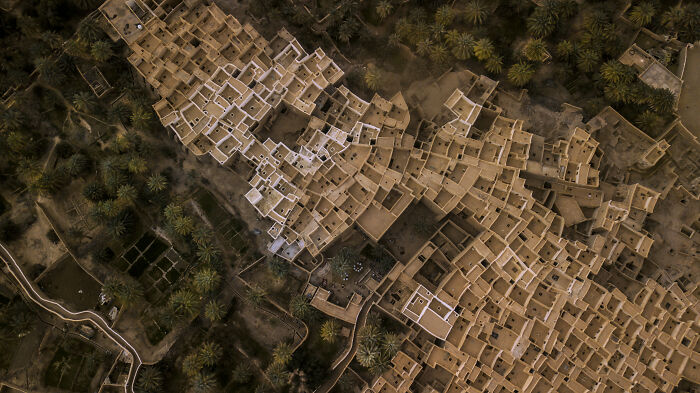 Aerial view of a stunning UNESCO treasure, showcasing ancient desert architecture surrounded by palm trees.