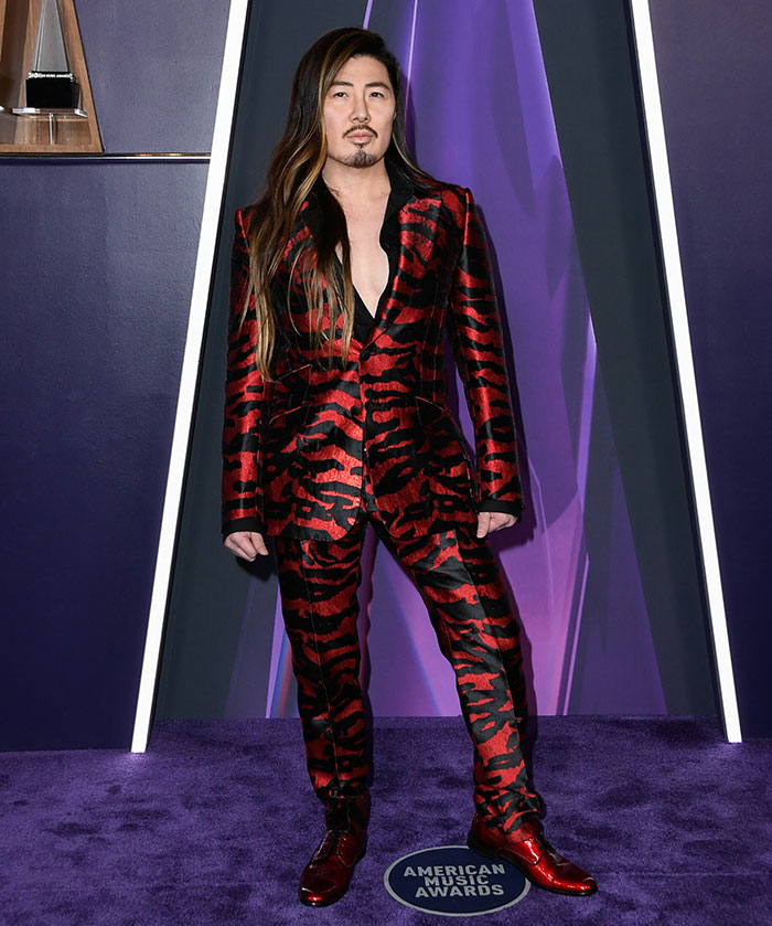 Celebrity at the American Music Awards wearing a bold red and black patterned suit showcasing worst dressed stars fashion.
