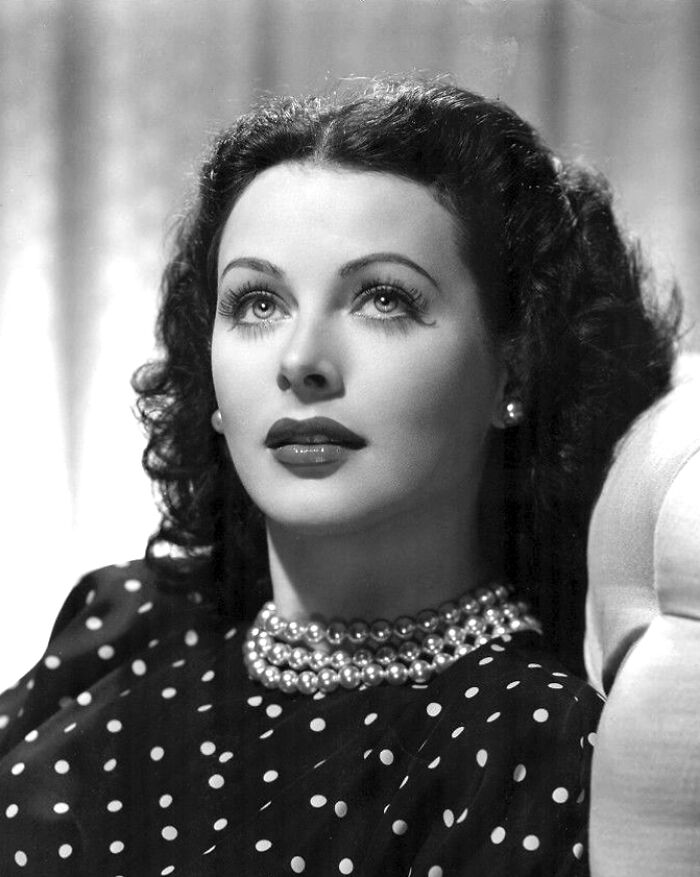 Elegant 1940s Hollywood icon with curled hair, pearl necklace, and polka dot dress portraying glamorous vintage style.