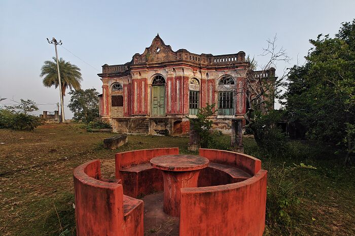 Old red circular seating area in front of a historic building in Simultala, a timeless escape from the modern world.