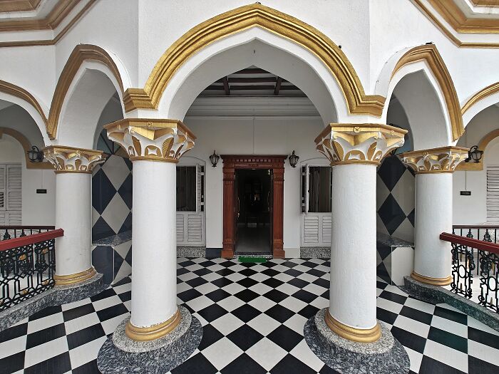 Ornate white and gold pillars with arched ceilings and checkered flooring in Simultala historical architecture.