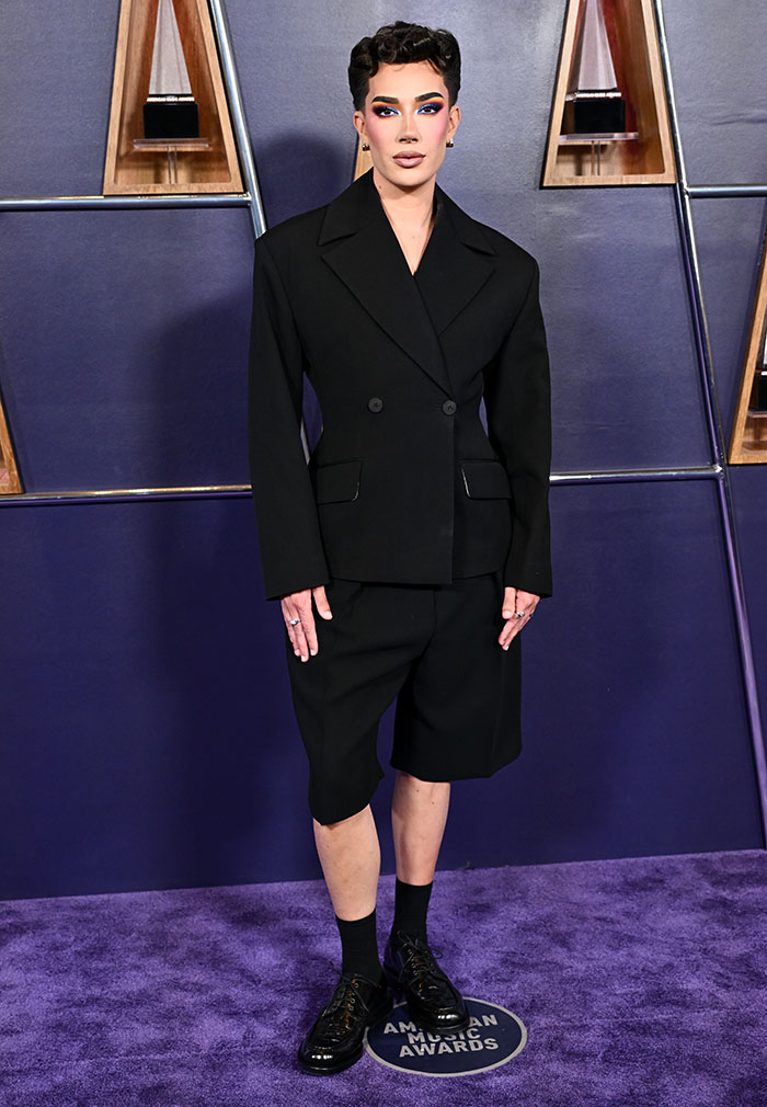 Person wearing an oversized black blazer and shorts with bold makeup on the carpet at the 2025 American Music Awards worst dressed stars.