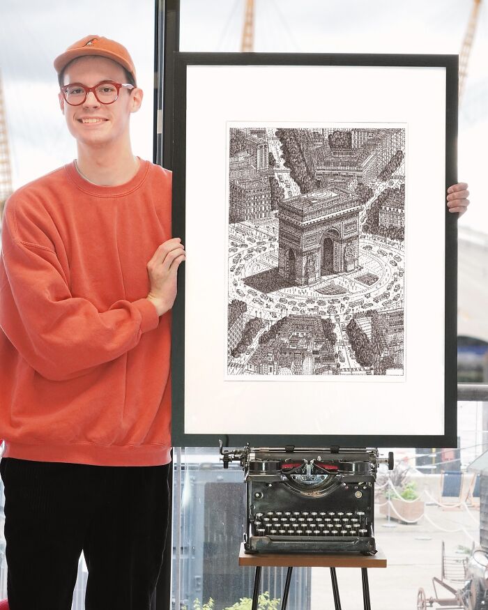 Young artist showcasing detailed drawing of Arc de Triomphe created with a typewriter, standing beside the vintage machine.