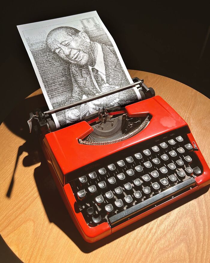 Red typewriter on a wooden table creating an impressively detailed portrait drawing using typewriter art technique.