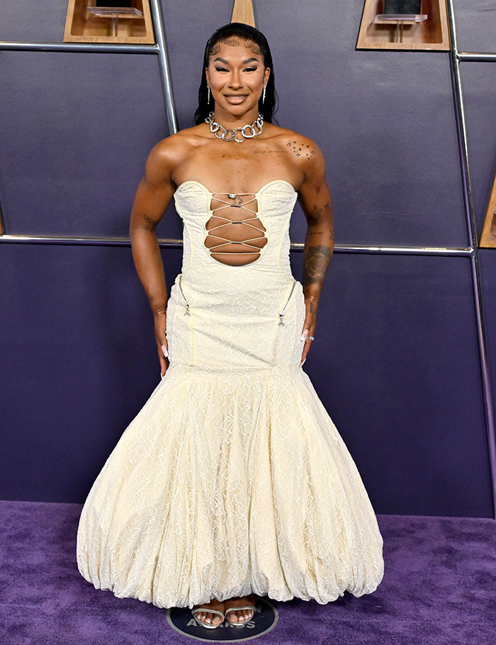 Person posing in a lace cream dress with cutout details, featured among worst dressed stars from the 2025 American Music Awards.