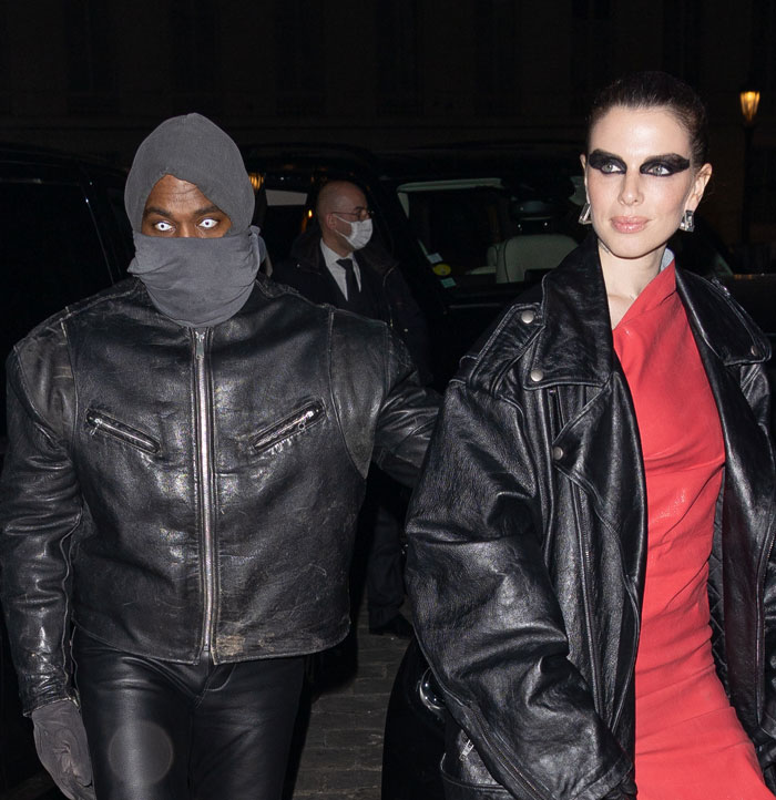 Julia Fox in bold makeup and leather jacket attending skincare launch event at night with a masked companion.