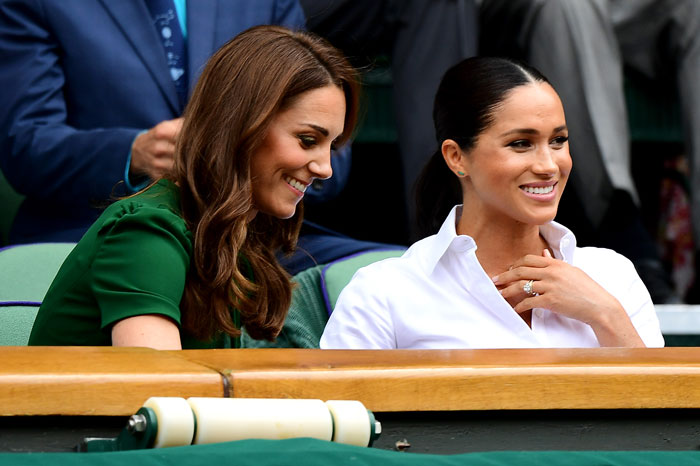Kate Middleton and Meghan Markle sitting together at an outdoor event, smiling and engaged in conversation.