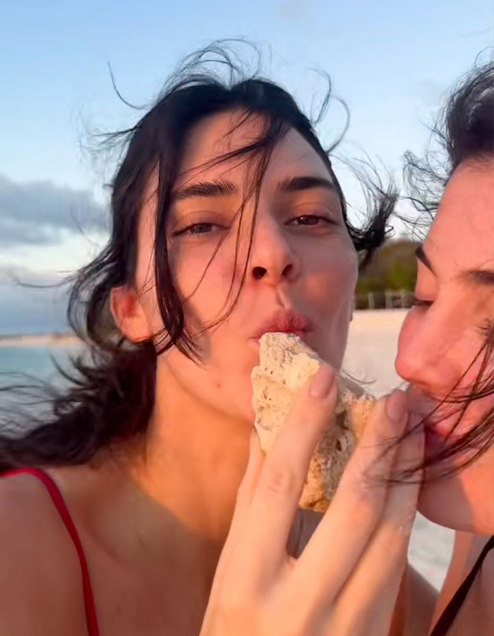 Kylie and Kendall Jenner on a beach, sharing a playful moment while enjoying a sunset walk together.