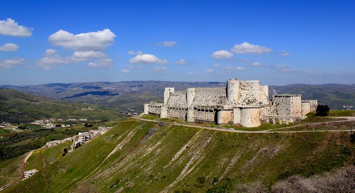 Ancient UNESCO treasure castle perched on a green hill with expansive valley and blue sky in the background