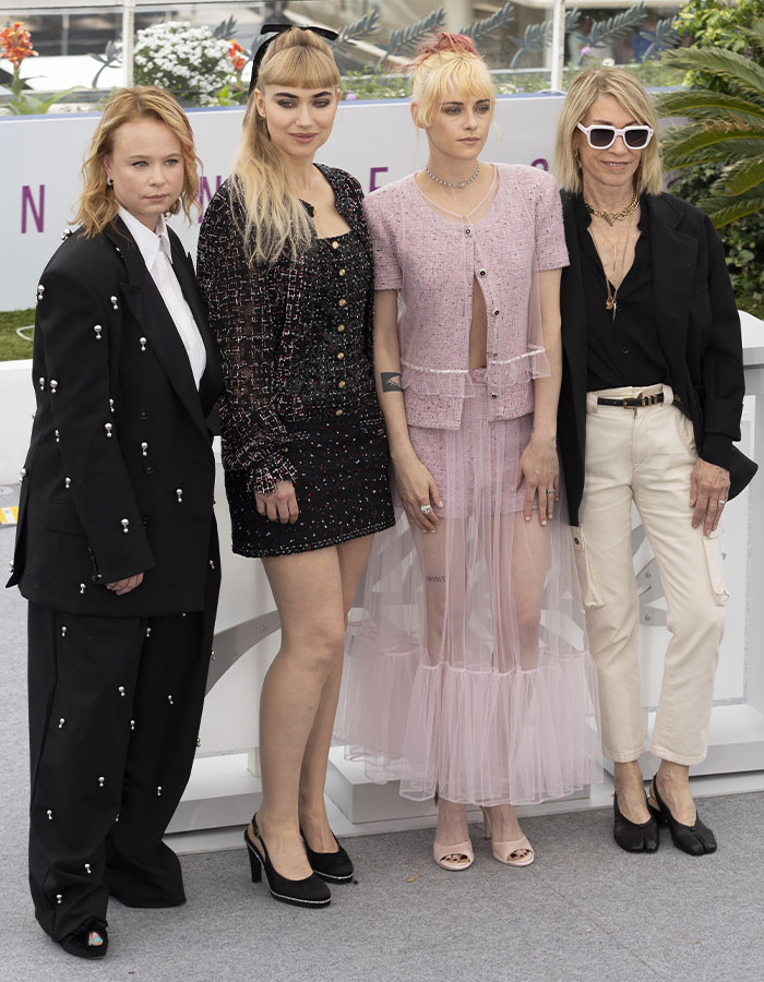 Kristen Stewart and others posing at an outdoor event, highlighting her viral Mine tattoo and its meaning.