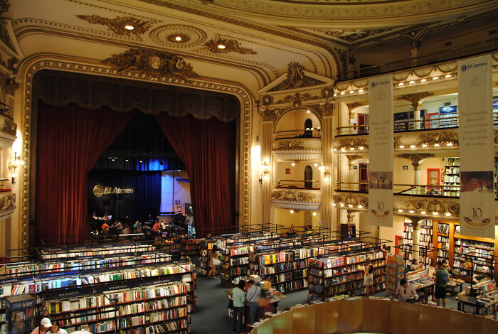 Impressive bookstore with grand architecture, ornate balconies, and rows of bookshelves filled with colorful books.