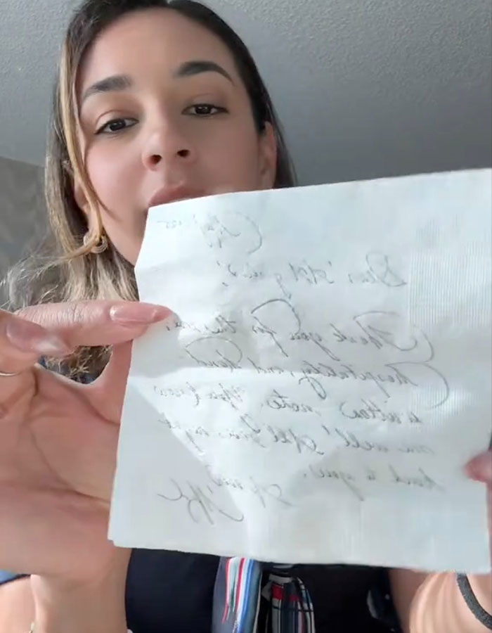 Woman holding handwritten note, illustrating Meghan Markle's note to flight attendant going viral online.