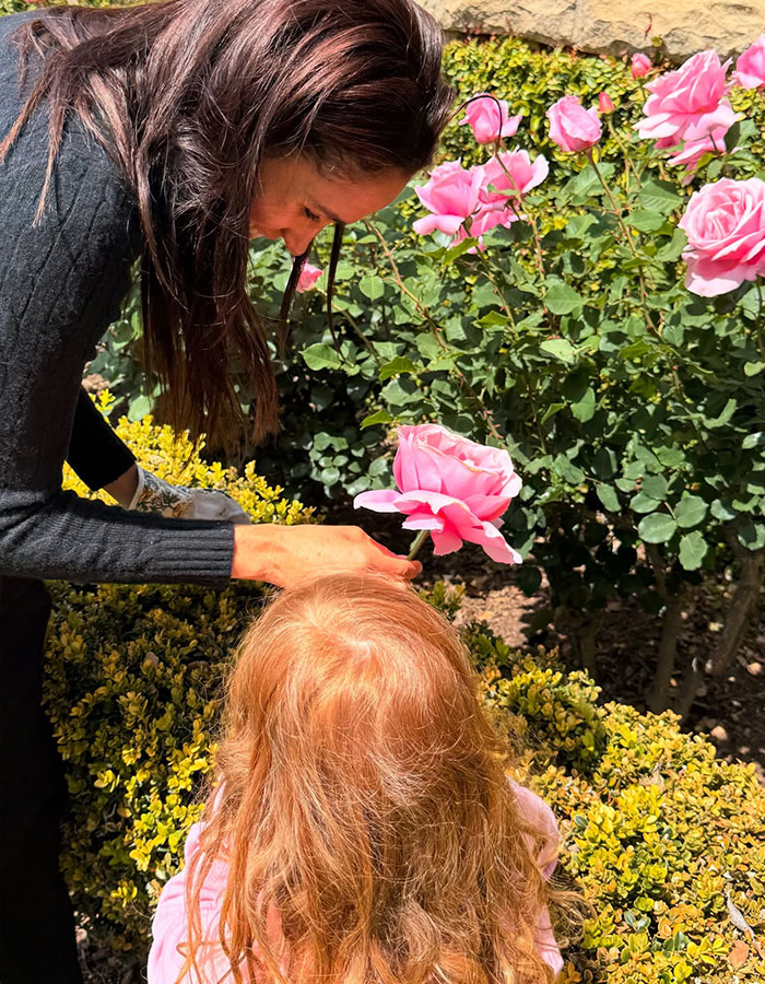 Meghan Markle shares a Mother&rsquo;s Day moment with children Lilibet and Archie among pink roses in a garden setting.