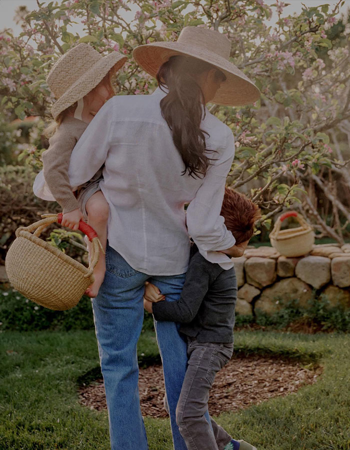 Meghan Markle outdoors with children Lilibet and Archie in garden wearing hats, sharing a warm family moment on Mother&rsquo;s Day.