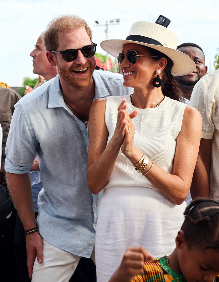 Meghan Markle wearing sunglasses and a hat smiling with Prince Harry outdoors in a candid moment near Montecito.
