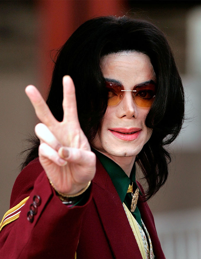 Michael Jackson wearing sunglasses and a red jacket, making a peace sign with his hand, sparking iconic lean doubts.