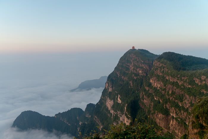 Mountain peak with a small structure surrounded by clouds, showcasing one of the hidden UNESCO gems in a natural setting.