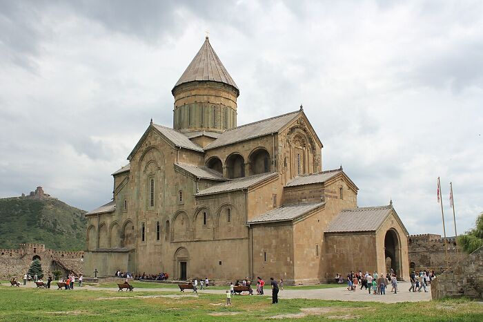 Historic stone UNESCO site with visitors exploring ancient architecture under a cloudy sky, highlighting hidden gems.