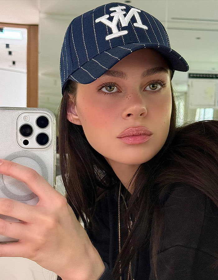 Young woman wearing a blue cap taking a selfie indoors, highlighting Bella Thorne's warning about Brooklyn Beckham wife Nicola Peltz.