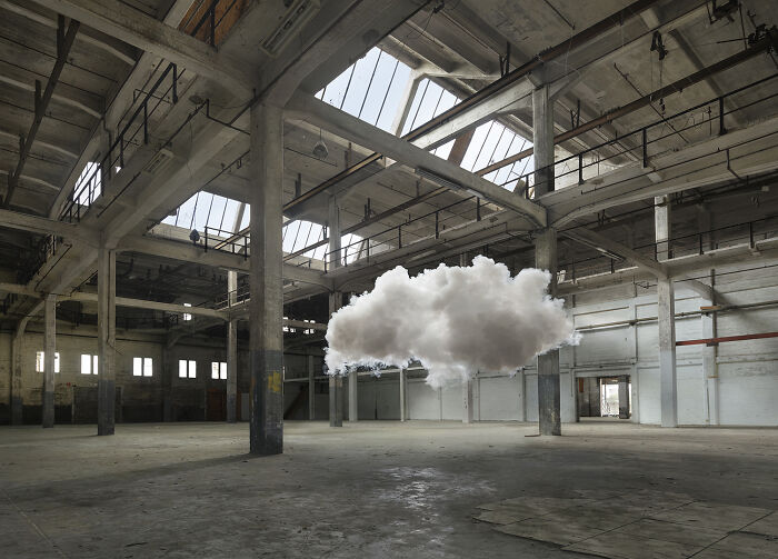 Realistic cloud made from smoke and water vapor floating inside an industrial indoor space with high ceilings.