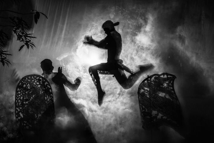 Silhouetted dancers captured in a single frame with dramatic lighting and smoke, showcasing powerful one shot photography.
