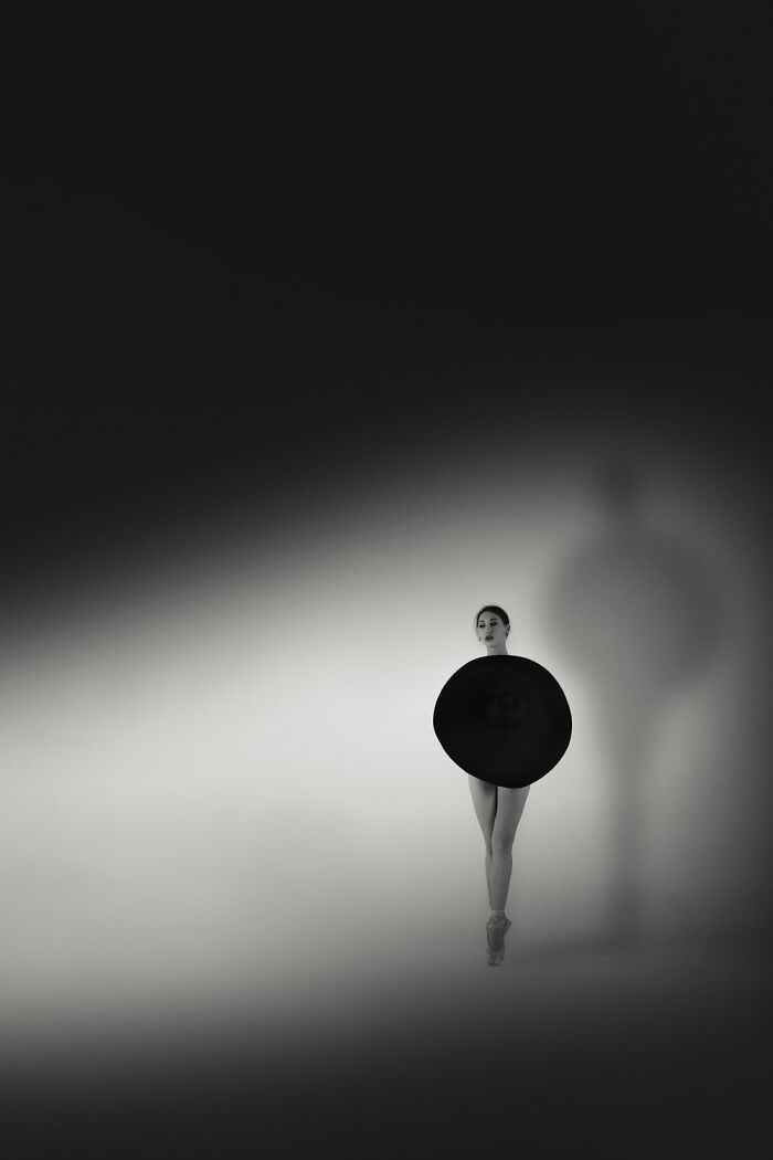 Minimalist black and white photo of a ballerina posing with a large circular prop in 2025 one shot photo contest.