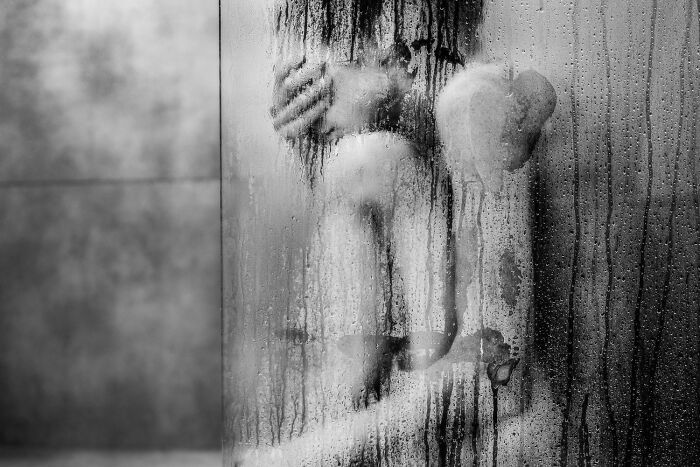 Black and white photo of a person sitting behind a wet glass pane, showcasing the power of a single frame photography.