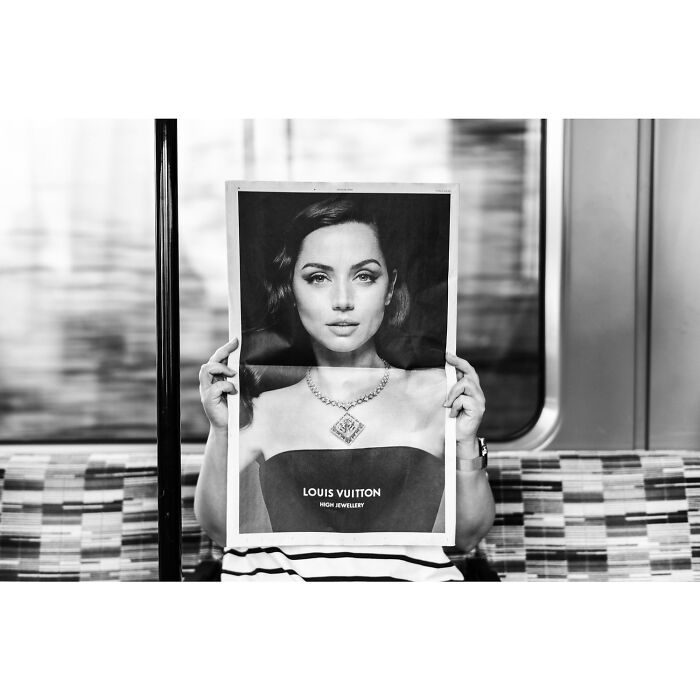 Person on subway holding a black and white photo of a woman's face showcasing the power of a single frame.