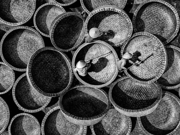 Black and white aerial shot of workers with large woven baskets showcasing the power of a single frame in 2025 photo contest.