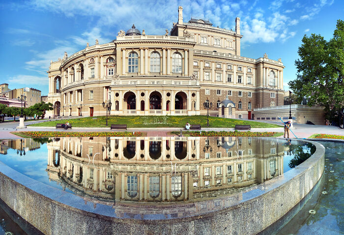 Stunning UNESCO treasure reflected in water with clear blue sky, historic architecture, and surrounding greenery.