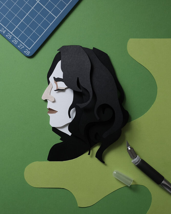 Paper art portrait of a woman with black hair on green background, showcasing intricate and colorful paper art design.