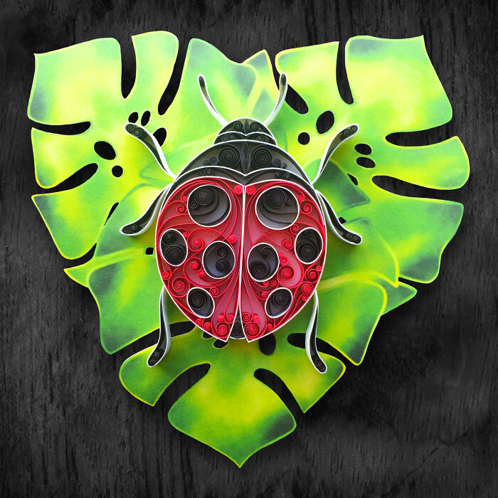 Colorful and intricate paper art of a ladybug on a green leaf showcasing detailed quilling techniques and vibrant design.