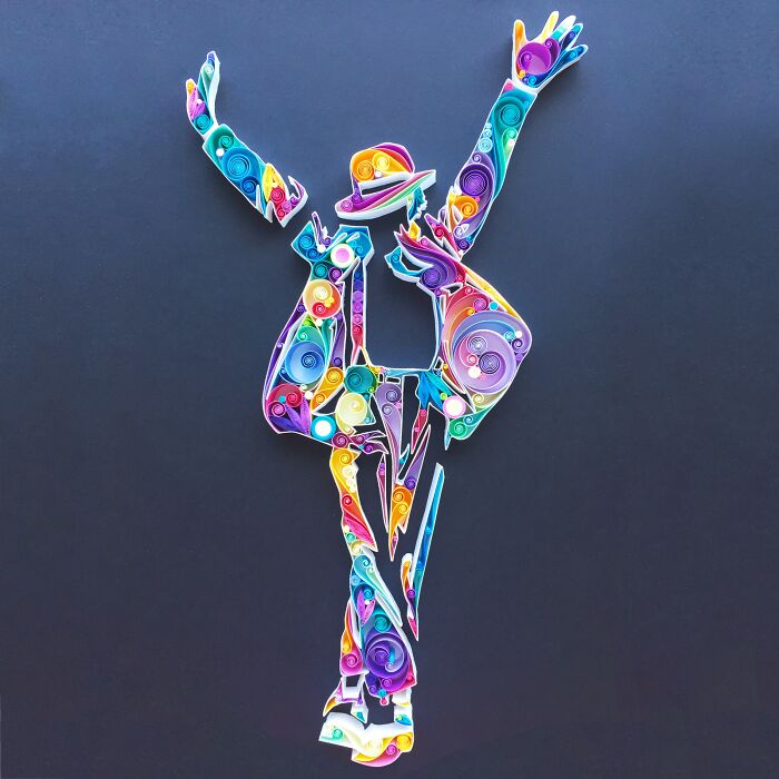 Intricate, colorful paper art figure of a dancing person made with detailed quilling techniques on a dark background.