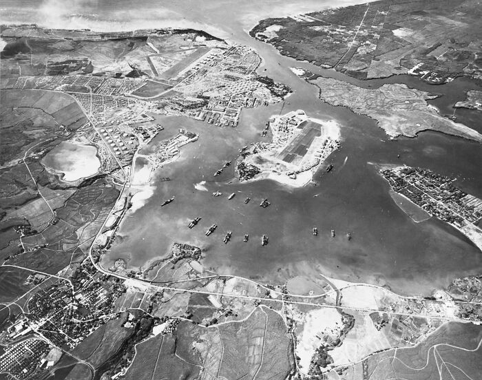 Aerial black and white photo of a harbor with ships and surrounding land showing one of the biggest mistakes in history.