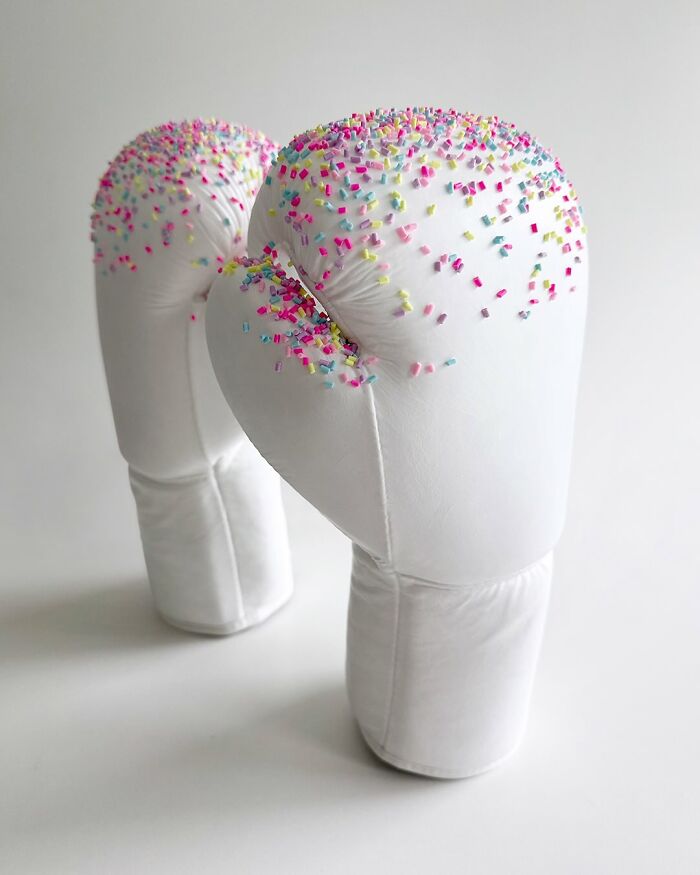 White boxing gloves covered with colorful sprinkles, showcasing unique artworks with a burst of color effect.