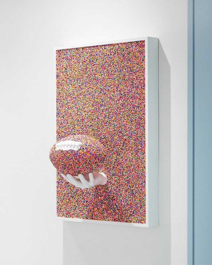 Colorful artwork of a football covered in sprinkles held by a white hand, showcasing unique sprinkle art by Pepe Bratanov.