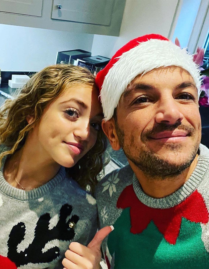 Princess Andre smiling with a man in a Santa hat, wearing festive sweaters, showcasing a holiday atmosphere indoors.