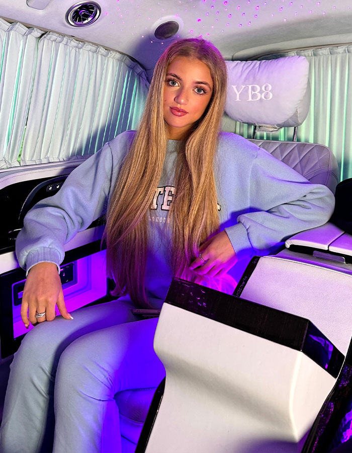 Princess Andre, 17, sitting inside a luxury car with neon purple lighting, showcasing her new $13,000 vehicle.